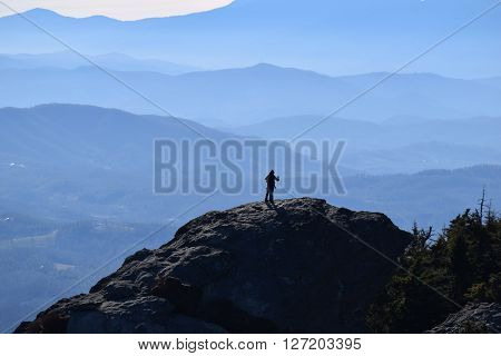 Silhouetted man reaching off towards blue mountains of North Carolina