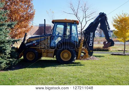 NAPERVILLE, ILLINOIS / UNITED STATES - NOVEMBER 3, 2015: A John Deere 310SJ backhoe sits parked in the Naperville Park District's Wildflower Park.