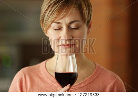 Beautiful middle-aged woman tasting red wine, close-up