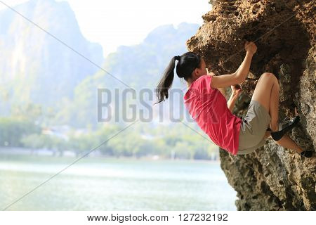 young woman rock climber climbing at seaside mountain rock