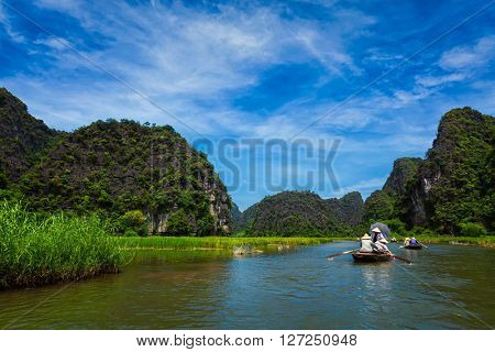 Tourists on boats in Tam Coc-Bich Dong Ngo Dong river in popular tourist destination near Ninh Binh, Vietnam