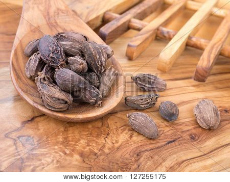Amomum pods in the wooden spoon on the olive wood cutting board