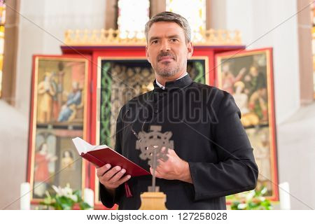 Priest in church with bible in front of altar