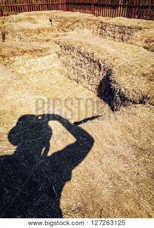 Photographer's shadow and haystacks. Straw bales. Silhouette of man. Rural scene. Photography theme. Light and shadow.
