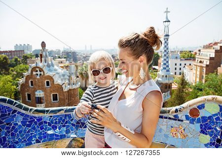 Happy Mother And Baby Checking Photos In Camera At Park Guell