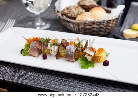 Salted and marinated herring on creamy cheese, beer and black bread chips, potatoes and red caviar