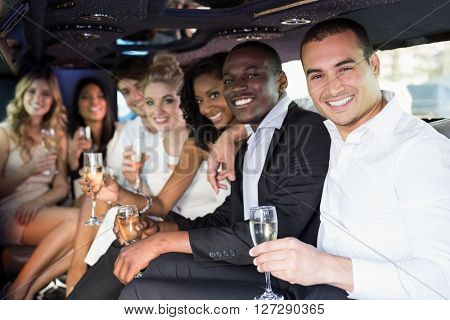 Well dressed people drinking champagne in a limousine on a night out
