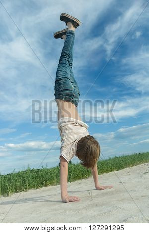 Handwalking of teenage boy on dirt road at green farm field background outdoors