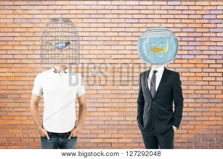 Businessperson and casually dressed man with fishtank and birdcage instead of heads on brick background