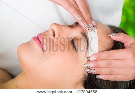 Closeup womans face receiving facial hair wax treatment, beauty and fashion concept.