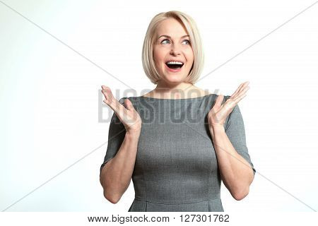 Surprised happy woman looking sideways in excitement. Isolated over white background. Portrait of happy aged woman.