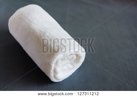 Rolled up white towel on fabric background.