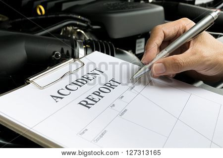 Mechanic Inspecting damage car and filling in accident report form