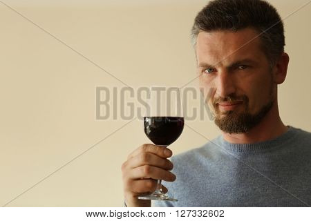 Handsome middle-aged man tasting red wine, close-up