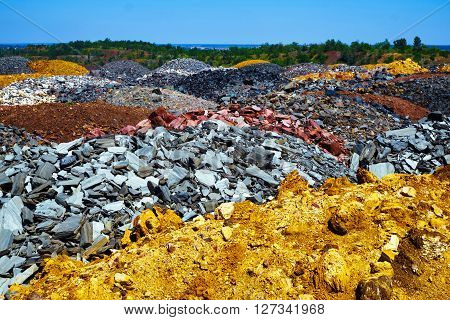 Colorful dumps of depleted iron ore with trees on background