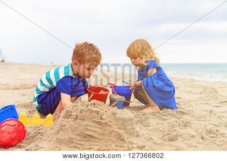 kids play with sand on summer beach, family vacation