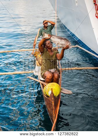 Hell-Ville Madagascar - December 19 2015: Malagasy vendors from their outrigger canoe offer crabs fish and tropical fruits to ship passengers at Hell-Ville Nosy Be Island Madagascar.