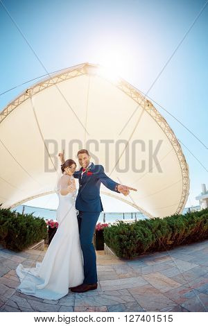 Young wedding couple enjoying romantic moments dansing and have fun outside against modern buildings. Fisheye lens