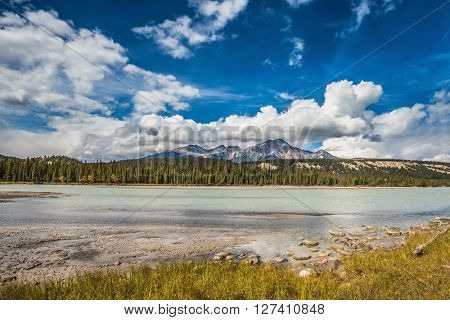 Beneaped Medicine Lake in the fall. Evergreen forests and snow-capped Rocky Mountains of Canada
