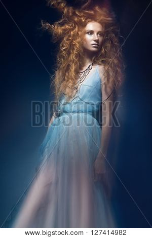Beautiful fashionable red-haired girl in a transparent dress in mermaid image with creative hairstyle curls. Fashion beauty style. Photos shot in a studio with a mixed light