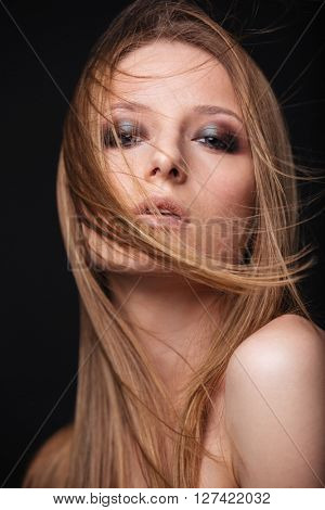 Beauty portrait of a lovely woman with fresh skin looking at camera over black background
