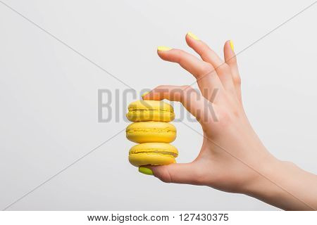 Person holding three yellow macaroons in her arm