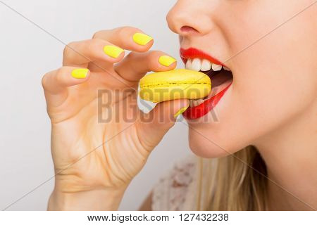 Woman taking a bite of yellow macaroon