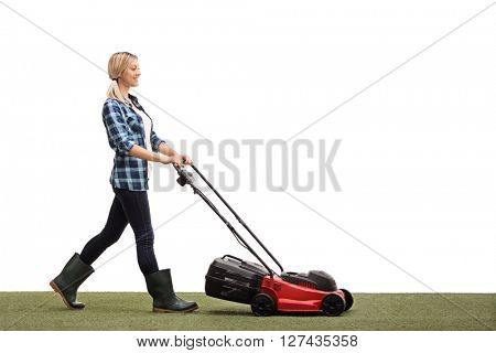 Profile shot of a young cheerful woman mowing a lawn with a lawnmower isolated on white background
