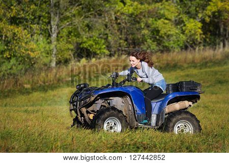 Elegant woman riding extreme quadrocycle ATV on a meadow