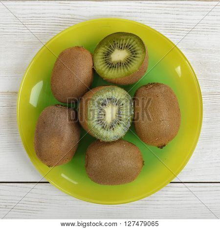 Halves and whole kiwi placed on a plate. Top view. Helping digestion with enzymes. Boosting immunity. Creating alkaline balance. Naturally organic food. Premier Antioxidant Protection.