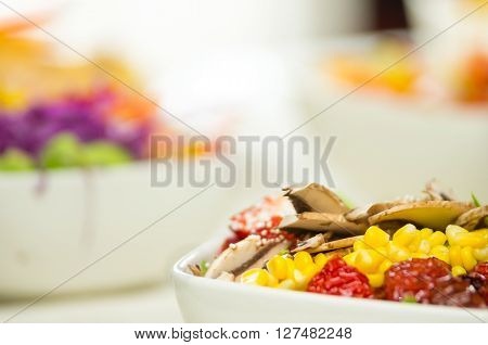 Closeup delicate fresh presentation of salad in white bowl with colourful vegetables such as mushrooms, corn and sundried omatoes.