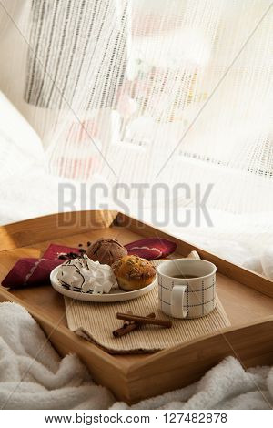 Sweet breakfast in bed served on tray with coffee and cupcakes