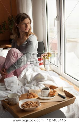 Healthy breakfast in bed served on tray with coffee, cornflakes, croissant and milk. Woman having her breakfast in bed.