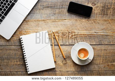 Working place at home on wooden table with laptop, notebook, phonel and cup of coffe