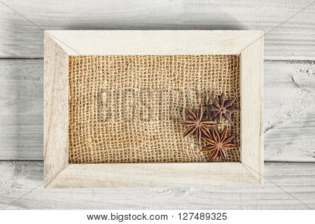 Frame with anise on a wooden board.