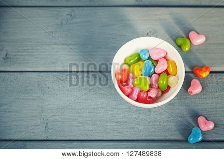 Colored pills in a circular plate on a wooden background.