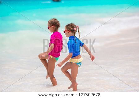 Adorable little girls have fun on white beach during vacation