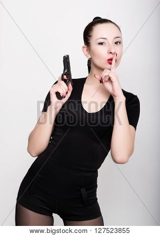 leggy slim beautiful sexy girl in lacy lingerie on a high heels,  holding gun, raised his index finger to his lips, posing.