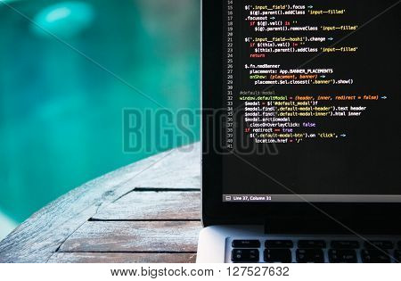 laptop on a wooden table against the background of accepted Swimming pool