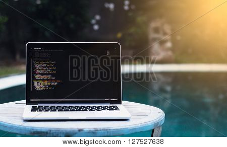 laptop on a wooden table against the background of accepted Swimming pool