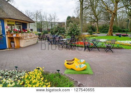 Lisse, Netherlands - April 4, 2016: Typical yellow dutch wooden clogs or klompen, painted with windmill and Keukenhof park view