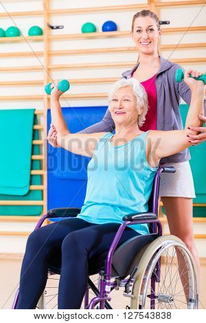 Senior woman in wheel chair doing physical therapy with her trainer