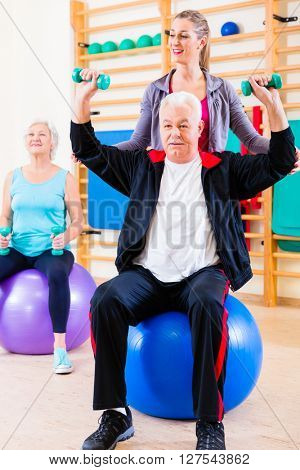 Physiotherapist coaching senior people exercising with dumbbells