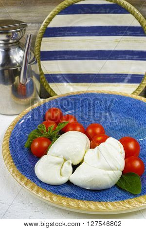 Traditional italian mozzarella buffala with tomatoes and basil on blue plate copy space