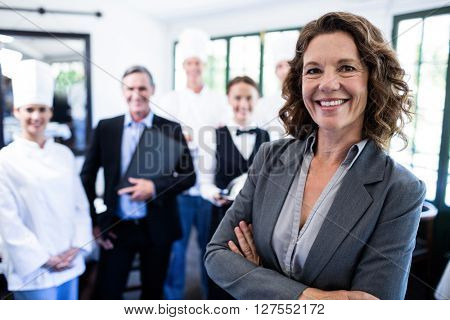 Portrait of happy female manager standing with arms crossed in restaurant