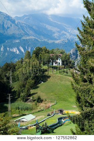 a white house and a playground on top of a hill at Piani d'Erna (part of the Alps) near Lake Como in Italy