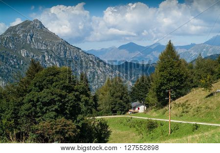 photo of a sunlit traditional house at Piani d'Erna (part of the Alps) near Lake Como in Italy