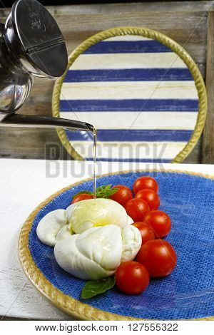 Traditional italian mozzarella buffala with tomatoes and basil on blue plate copy space
