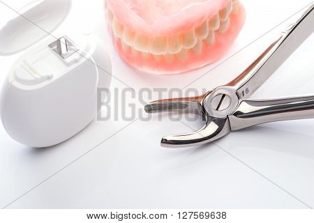 Teeth Model With Dental Floss And Forceps On White Background