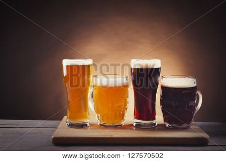 Different sorts of draft beer in glasses on wooden table. Retro stylization